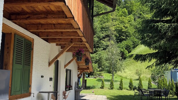 A wooden building with a balcony, a stone pathway, and a grassy garden. - Your time-out with a view of the Alps and the Kander (Kandergrund)