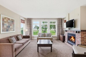 Ein Wohnzimmer mit Kamin, Fernseher, Sofa und Couchtisch.