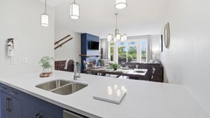 Una cucina moderna con una grande isola, elettrodomestici in acciaio inossidabile e luci a sospensione.