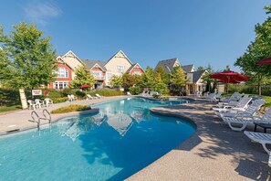 Ein Swimmingpool mit Liegestühlen und Sonnenschirmen, umgeben von Gebäuden im traditionellen Baustil.