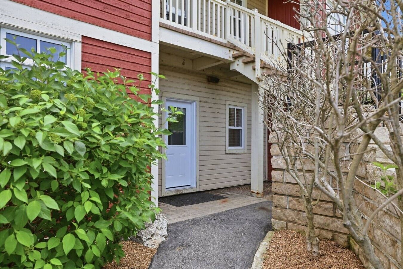 A two-story building with a red exterior, a white door, and a small porch.