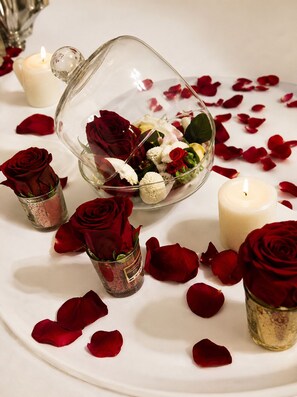 A table with a glass pitcher, candles, and roses.