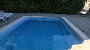Een rechthoekig zwembad met een betegeld zonnedek eromheen.