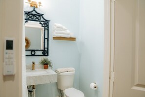 A bathroom with a toilet, sink, and mirror. - Sugar`s Inn Room #4 | Romantic Stay Near Galveston Cruise Port & Downtown (Galveston)