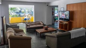 A living room with a sofa, armchair, and a coffee table. A television is on a wooden stand.