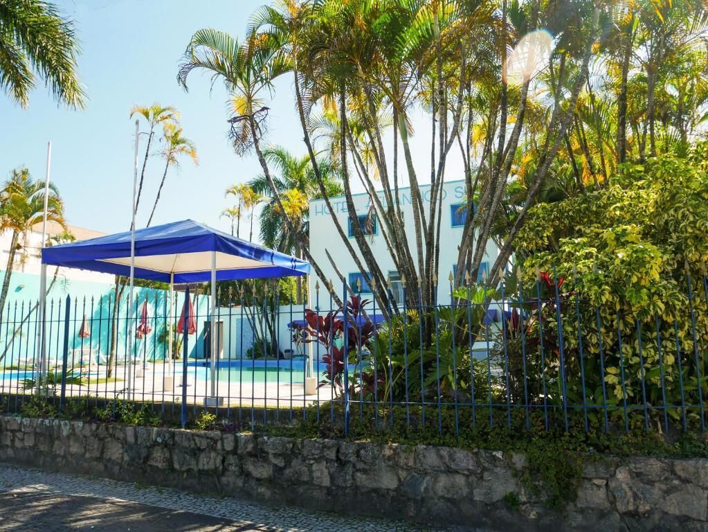 A hotel with a pool area, surrounded by palm trees and a stone wall.