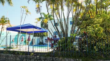 A hotel with a pool area, surrounded by palm trees and a stone wall.