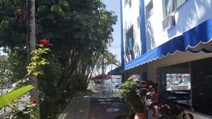 Un bâtiment doté d’un auvent bleu, de plantes en pot et d’un espace extérieur aménagé pour s’asseoir.