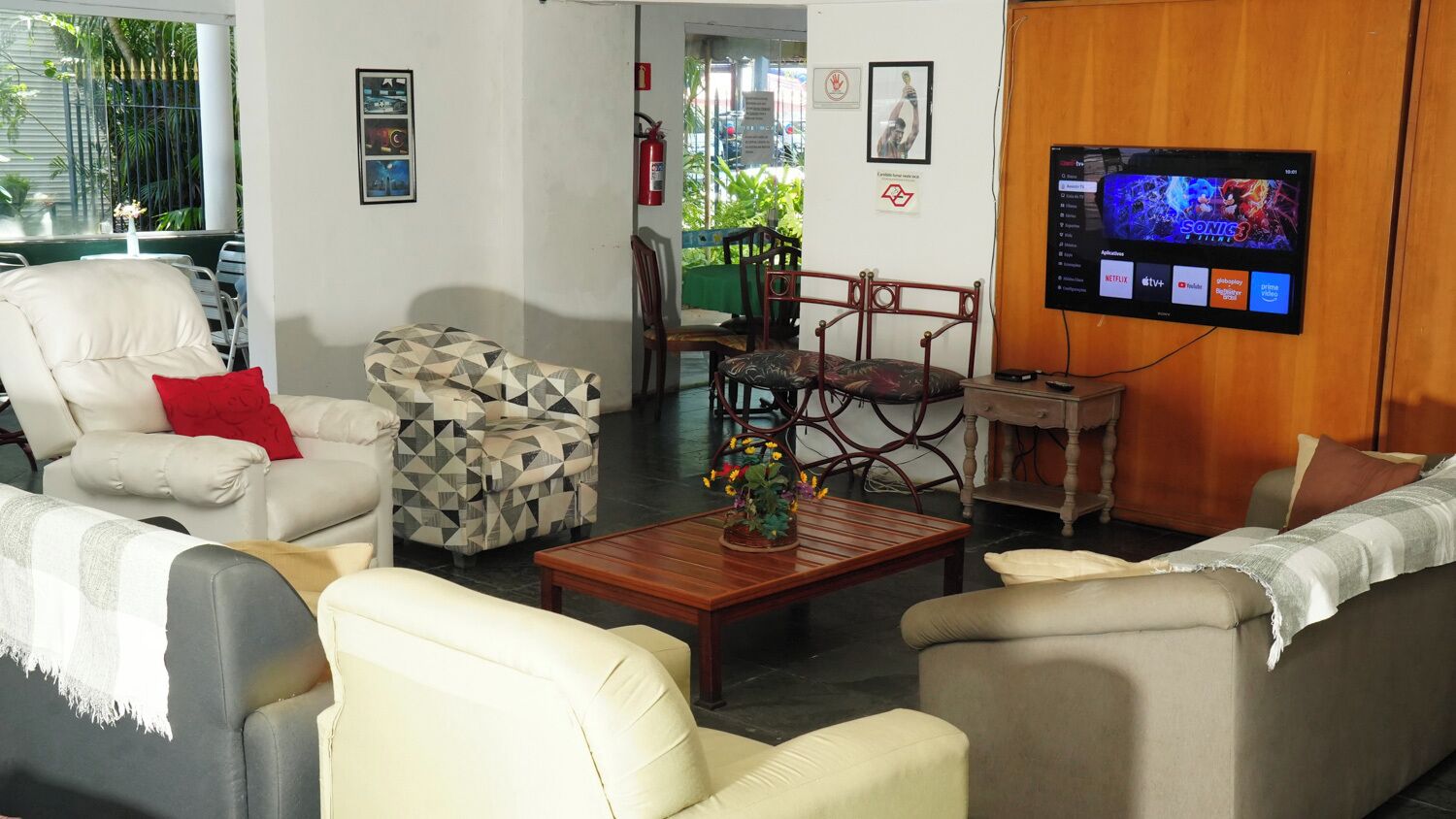 Una sala de estar con un sofá, sillones, una mesa de centro y un televisor montado en la pared.