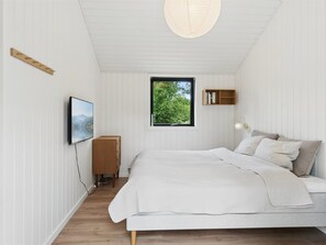 Ein Schlafzimmer mit Bett, Fenster mit Blick, Wand-Fernseher und Bücherregal.