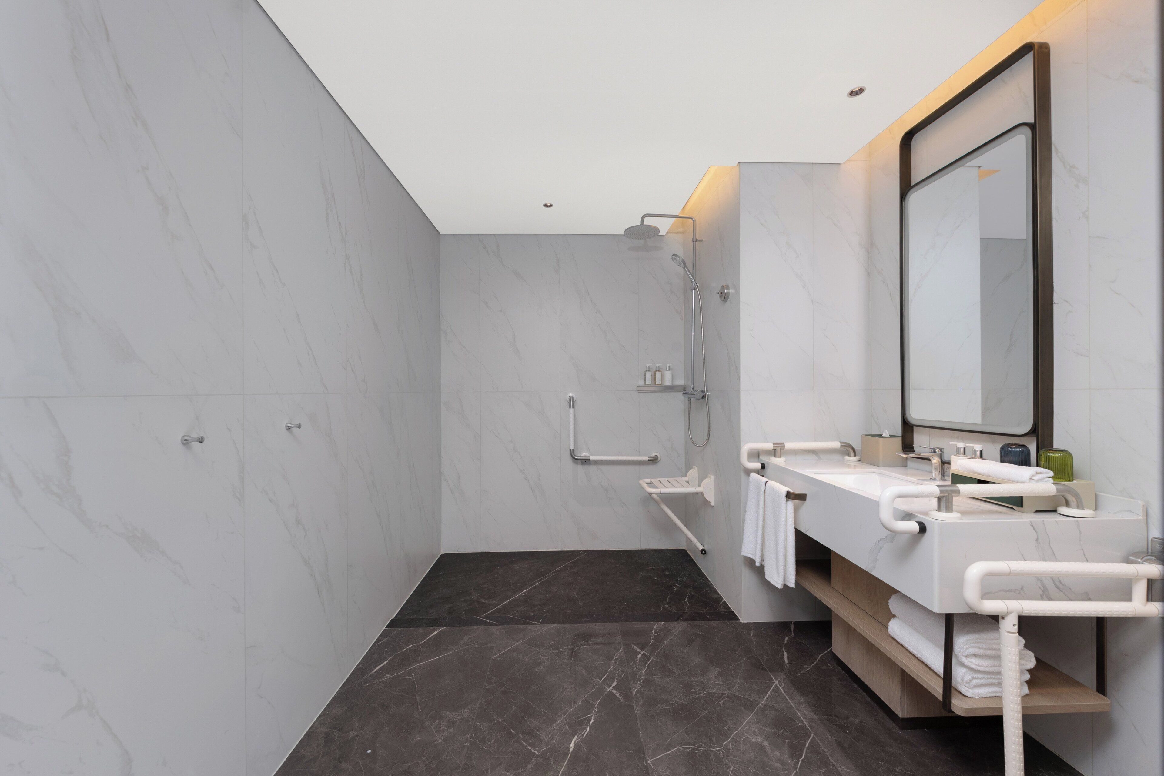 A modern bathroom with a shower, a sink with a mirror, and a towel rack.