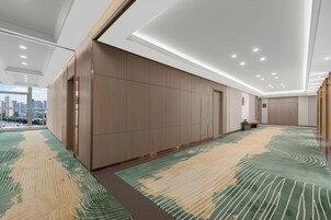 A modern hotel room with a large window, a patterned carpet, and a city view.