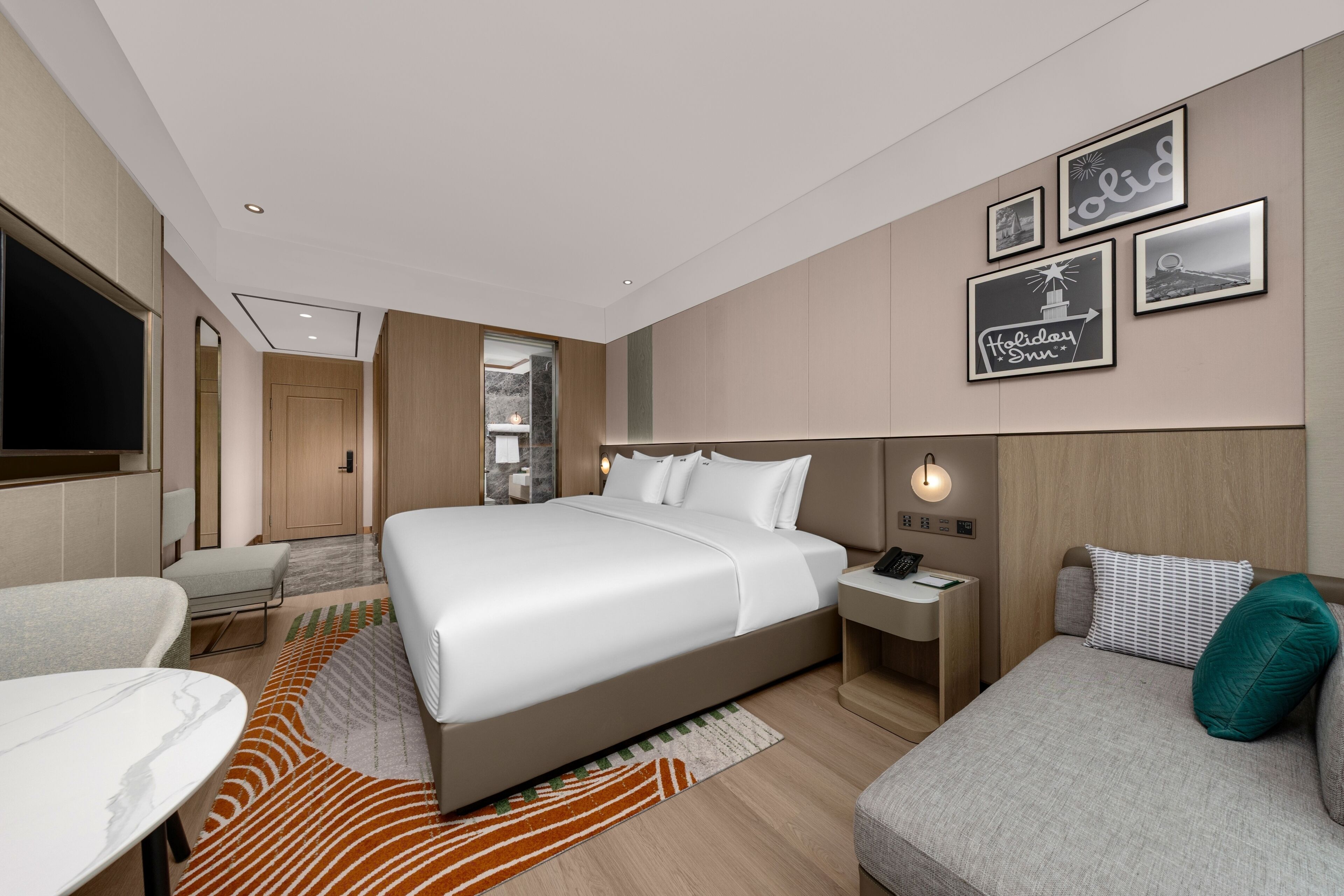 Habitación de hotel con una cama grande, un escritorio, una silla, un sofá y un televisor.