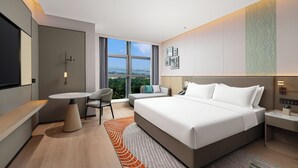 Une chambre d’hôtel moderne, dotée d’un grand lit, d’un bureau, d’une chaise et offrant une vue sur la ville.