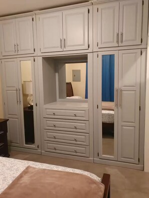 Ein Schlafzimmer mit einem Bett, einem Schminktisch und einem Kleiderschrank mit vielen Fächern.