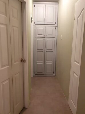 Ein schmaler Flur mit einem Schwebetürenschrank, einer Tür mit Griff und einem Lichtschalter an der Wand.