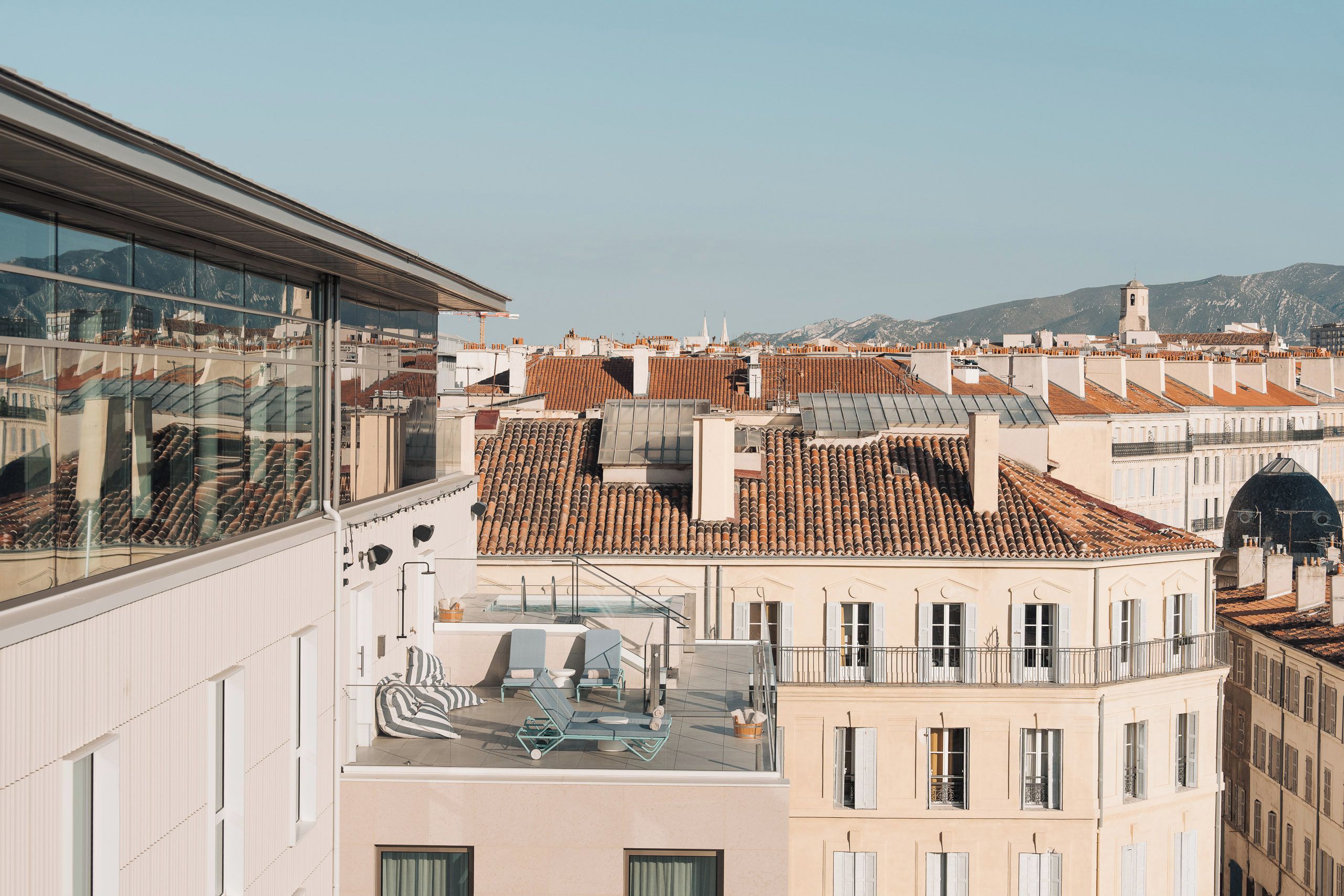 A high-rise building with a rooftop terrace featuring outdoor seating and a glass balustrade.