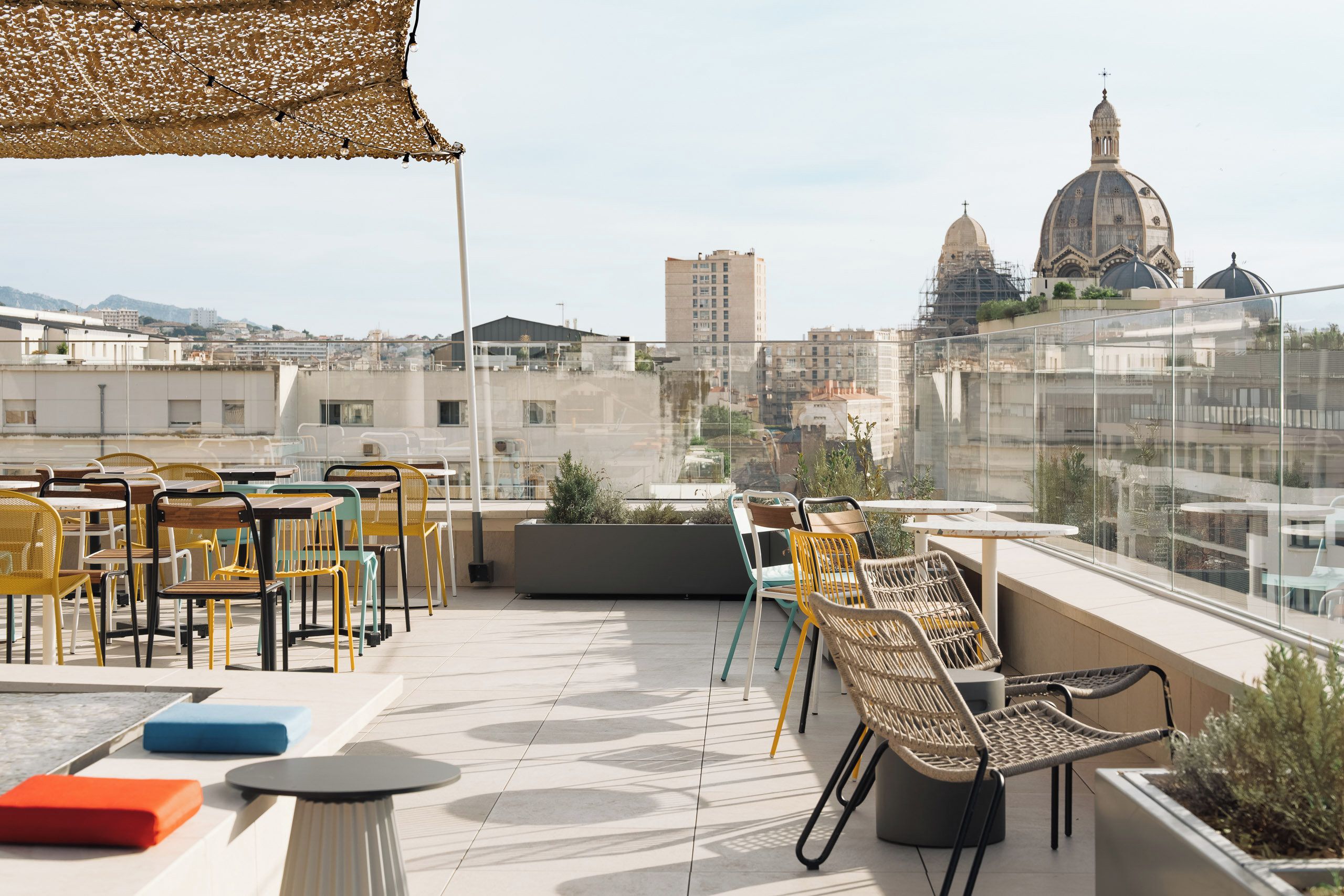 A rooftop terrace with outdoor seating, a view of a cityscape, and a building with a dome.