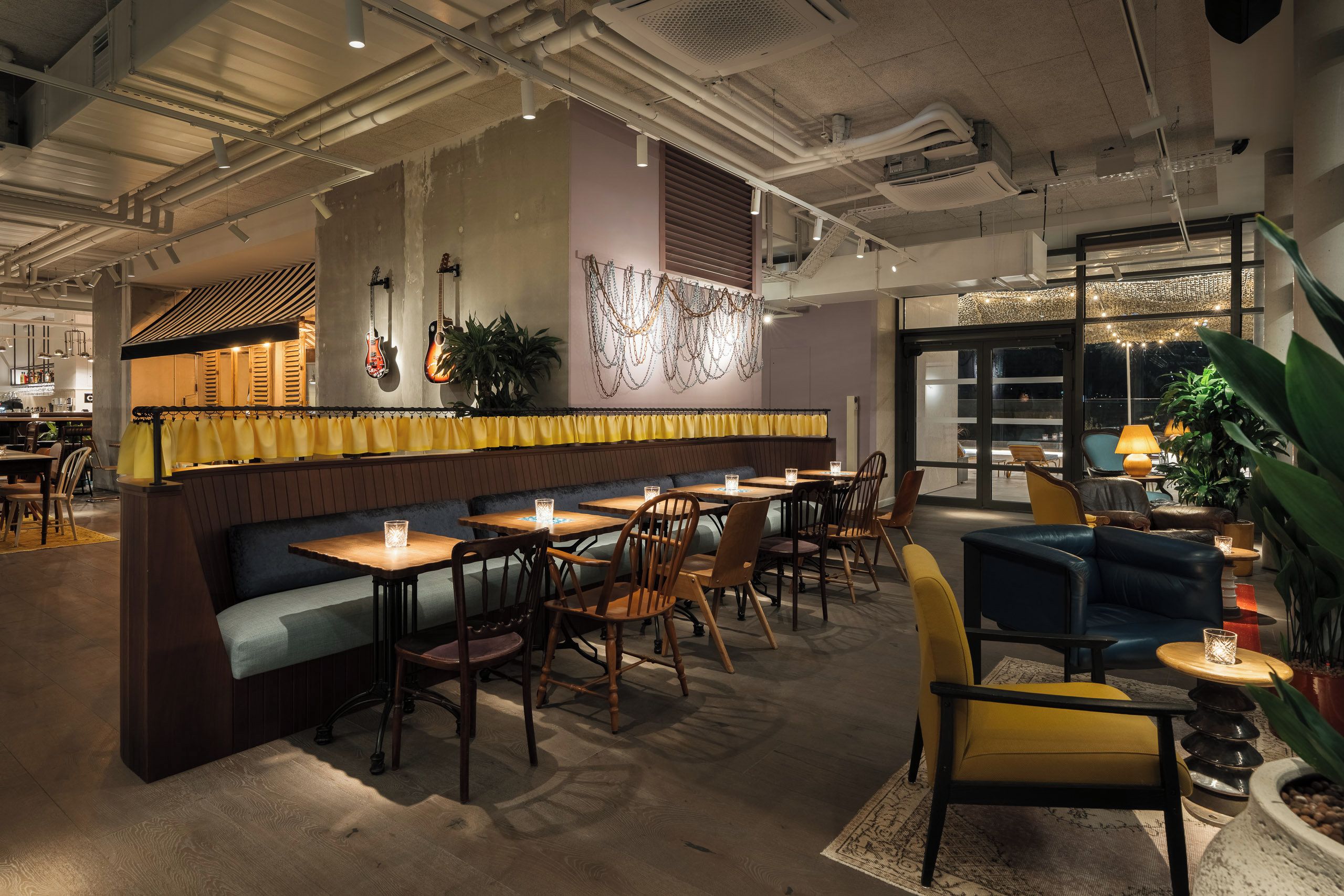 Een restaurantinterieur met een bar, zitplaatsen en uitzicht door grote ramen.