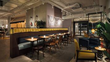 Een restaurantinterieur met een bar, zitplaatsen en uitzicht door grote ramen.