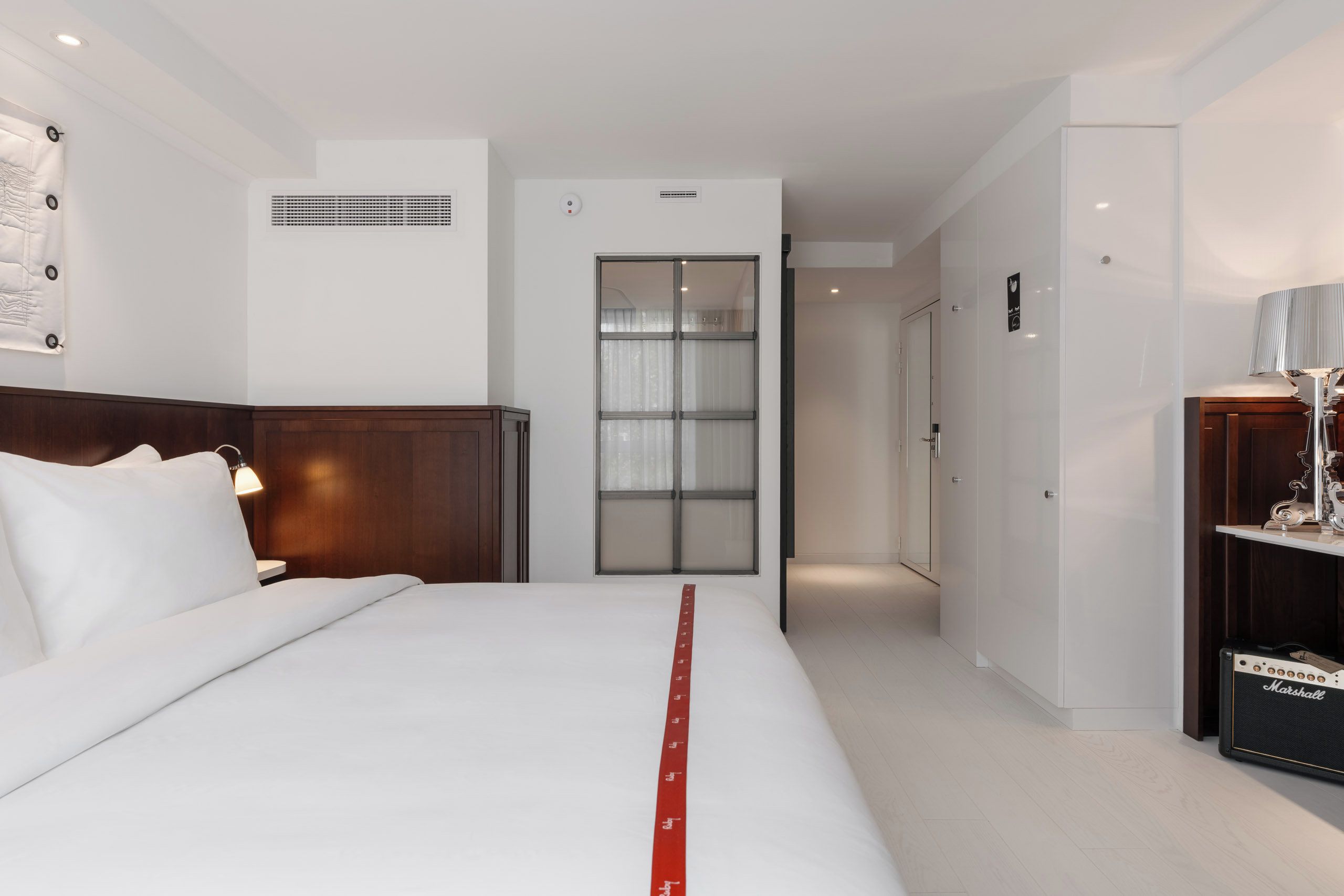 Une chambre d’hôtel avec un lit, une table de chevet, une lampe, une armoire et une porte de salle de bain.