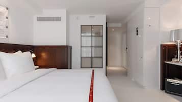 Une chambre d’hôtel avec un lit, une table de chevet, une lampe, une armoire et une porte de salle de bain.