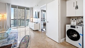 Un apartamento moderno con comedor, lavadora y vistas a edificios de gran altura.