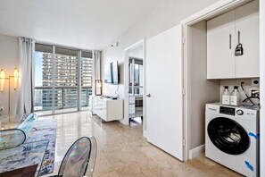 Eine moderne Wohnung mit Essbereich, Waschmaschine und Blick auf hohe Gebäude.