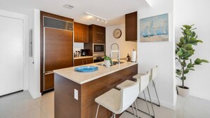 Eine moderne Küche mit Holzausbau, einer zentralen Kochinsel mit Barhocker, einer Uhr und einem Gemälde an der Wand.