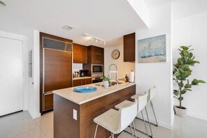 Eine moderne Küche mit Holzausbau, einer zentralen Kochinsel mit Barhocker, einer Uhr und einem Gemälde an der Wand.