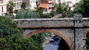 Un pueblo histórico con una imponente torre de iglesia, un puente de piedra y un río.
