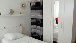 Un dormitorio con cama, armario, lámpara colgante y un adorno en la pared.