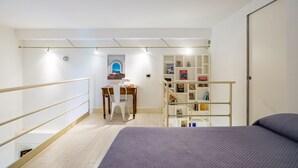 A bedroom with a bed, a desk with a chair, a bookshelf, and a window. - Chiaia Prestige by NapoliApartments (Naples)