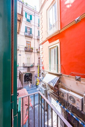 A narrow street with buildings on either side, a visible storefront with outdoor seating, and a pedestrian walkway. - Chiaia Prestige by NapoliApartments (Naples)