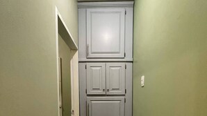 Ein schmaler Flur mit einer Tür am Ende, einem Lichtschalter an der Wand und einer kleinen Lücke zwischen Tür und Wand.