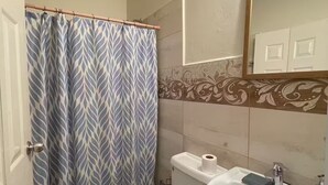Ein Badezimmer mit Toilette, Waschbecken, Duschvorhang und Spiegel.