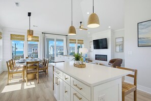 Eine moderne Küche mit einer großen Kochinsel, Holzstühlen und Pendelleuchten.