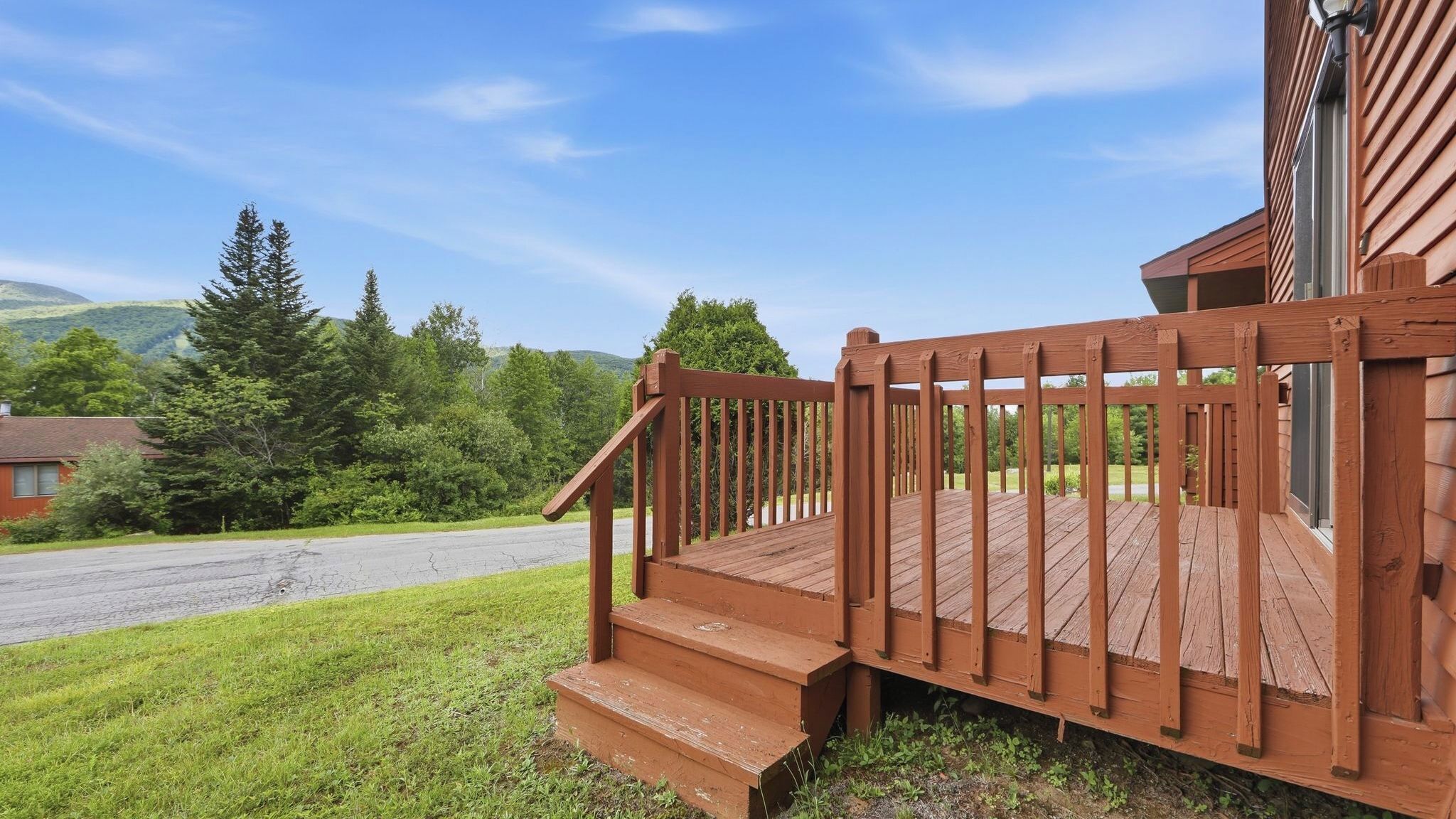 A wooden deck with a staircase leading to a house with a metal door.