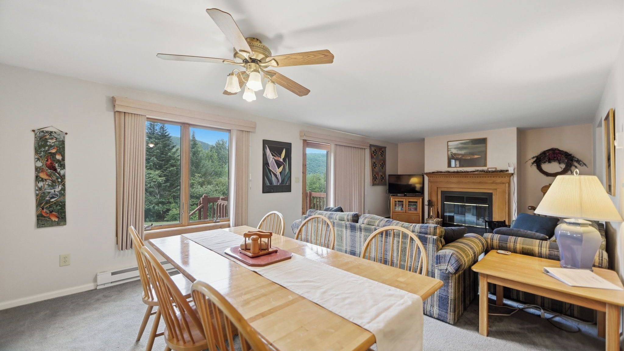 A dining area with a wooden table and chairs, a ceiling fan, and a fireplace.