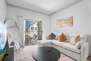 A modern living room with a sofa, a coffee table, and a TV. - Cortland 2202 (Houston)