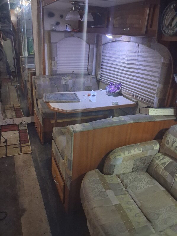 A compact living space with a sofa, a table with a book, and a window with blinds.