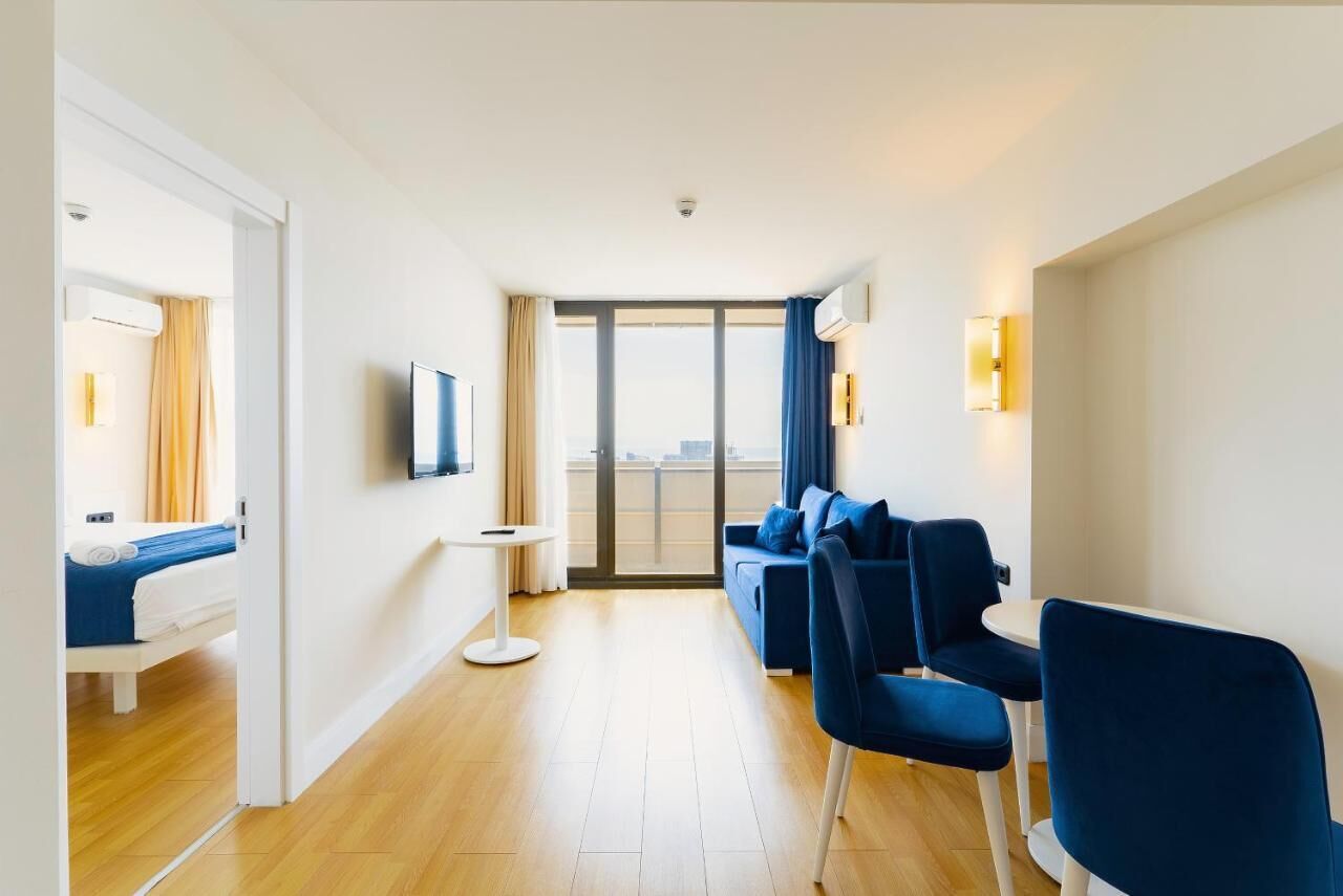 Et moderne hotelværelse med seng, sofa, fjernsyn, lille bord og en balkon med udsigt.