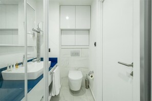 A bathroom with a white sink, blue countertop, white toilet, and a mirror. - Apart-Hotel Batumi City Orbi Central block C/D/A (Batumi)