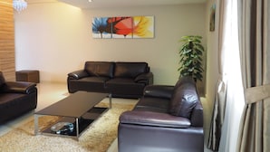 Ein modernes Wohnzimmer mit einem Ledersofa, einem Couchtisch und einer großen Pflanze.