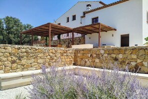 A white building with a stone wall and a covered outdoor seating area. - Finca Vegachi - Five Bedroom Villa, Sleeps 10 (Algatocín)