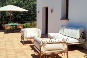 Un espace extérieur aménagé avec une table et des chaises, un canapé et un parasol.