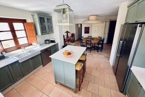 Una cocina con una isla central, un comedor con una mesa redonda y un refrigerador.