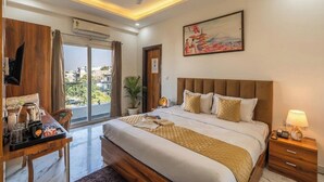 A hotel room with a bed, bedside table, desk with coffee maker, and a painting on the wall. - Coco House (Greater Noida)