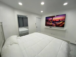 A bedroom with a large bed, a TV mounted on the wall, and a door leading to a balcony. - Beautiful Sapphire Suite (Sosúa)