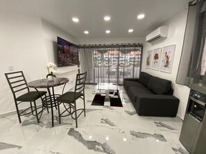 A modern living room with a marble floor, a round table with chairs, a sofa, and artwork on the walls. - Beautiful Sapphire Suite (Sosúa)